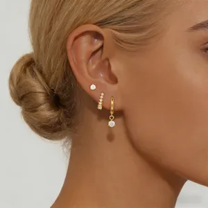 Primer plano detallado del elegante conjunto de pendientes de aro y tachuela dorados.