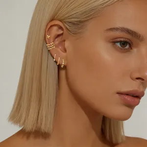 Close-up detail shot of dainty gold zircon ear cuff and stud earrings set worn by model.