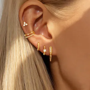 Detailed view of gold multi-piece crystal cartilage earrings, sparkling zircon studs and hoops set.