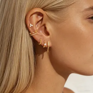 Detailed view of gold zircon floral earrings and cuff set worn on ear, elegant and shiny style.