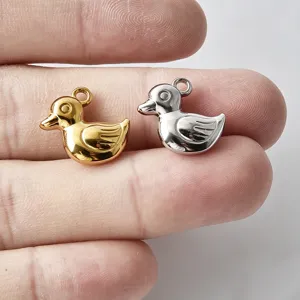 Gros plan de pendentifs canard en métal 3D, doré et argenté pour la fabrication de bijoux.