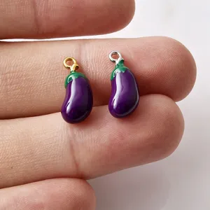 Close-up van schattige emaille aubergine bedels met gouden en zilveren lussen voor sieraden.