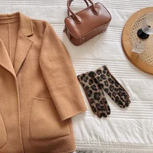 Detailansicht von Wollhandschuhen mit Leopardenmuster mit Kamelmantel und Tasche.