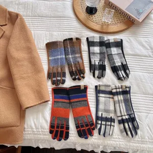 Detailansicht von vier Paaren klassischer Wollhandschuhe mit Karomuster auf weißer Tagesdecke.