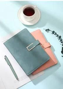 Detail of faux leather A5 notebooks with elegant gold U-shaped buckle and matching pen.