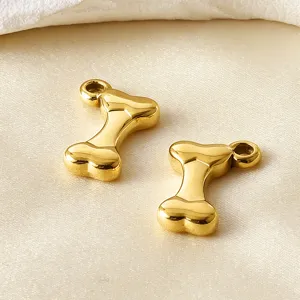 Primer plano de colgante de metal con forma de hueso dorado, ideal para joyería y collares DIY.