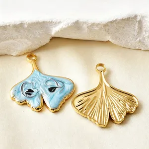 Detail shot of gold ginkgo leaf charms with blue enamel and engraved metal texture, perfect for DIY jewelry crafting.