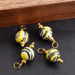 Nahaufnahme von gelben und schwarzen Perlen-Verbindern mit Goldösen für DIY-Schmuck.