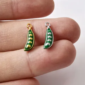 Close-up van kleine groene erwtenpeul emaille bedels met fijne metalen details en grootte.