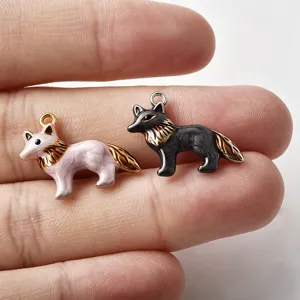 Close-up van schattige vos emaille bedels in roze en zwart voor DIY sieraden maken.
