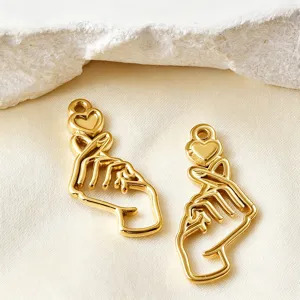 Gold tone finger heart pendant detail shot, hollow metal DIY jewelry charm accessory.