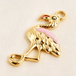 Gold-plated flamingo pendant close-up, pink enamel detail, shiny surface DIY jewelry accessory.