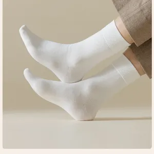 Close-up detail shot of men's plain white mid-calf thermal socks with ribbed cuffs.