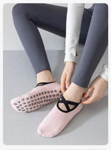 Dettaglio calzini da yoga rosa da donna con cinturini incrociati e suola antiscivolo.