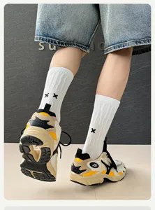 Detail shot of white ribbed cotton socks featuring contrast black cross embroidery streetwear style.