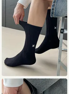 Close-up detail of black men's crew socks featuring white cross embroidery and great stretch.