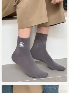 Close-up view of dark grey crew socks featuring mountain embroidery and ribbed elastic cuffs.