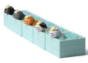 Detailansicht niedlicher Plastikkatzen-Figuren, die in winzigen Fliesen-Badewannen entspannen.