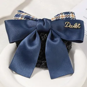 Close-up detail of dark blue satin bow hair net with tweed pattern and gold metallic accent.