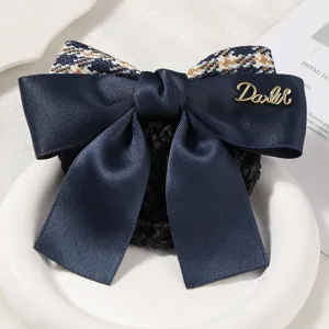 Dark blue satin bow hair net with houndstooth patch and metal letter decor for professional work.