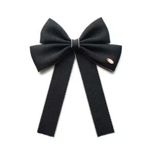 Black bow ribbon collar flower detail view with silver trim and metal badge ornament
