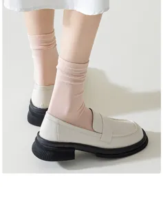 Close-up detail of women pink mid-tube socks paired with cream chunky platform loafers shoes.