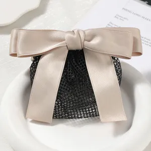 Closeup of a chic satin bow hair net, elegant khaki bow paired with durable black mesh.