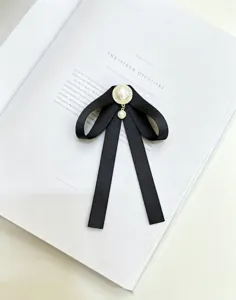 Détail broche nœud ruban noir, ornement de perle et pendentif, accessoire élégant style campus.