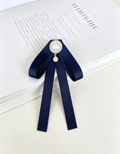 Détail de la broche nœud ruban bleu foncé avec perle et strass, élégant accessoire pour chemise.