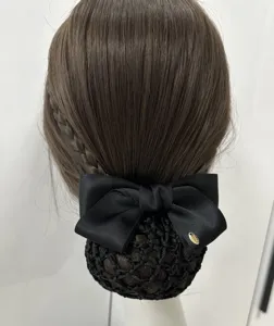 Close-up of a black satin hair bow with net bun cover, elegant professional hair accessory.