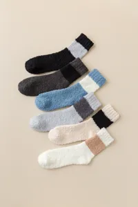Nahaufnahme von kuscheligen Korallenfleece-Schlafschuhen in bunten Farben mit Kontrastbündchen.