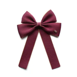 Detailed view of elegant burgundy bow with gold trim, premium fabric hair accessory and collar.