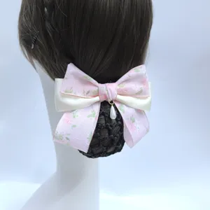 Pink floral lace hair net bow detail view featuring a delicate pearl pendant and black mesh.