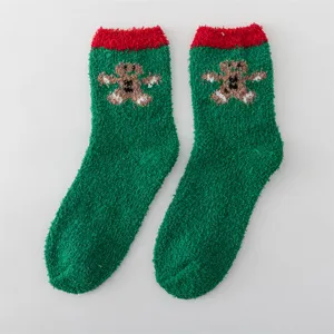 Cozy green fuzzy Christmas socks with red cuffs and cute gingerbread man pattern, ideal winter wear.