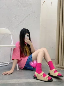 Nahaufnahme von hellrosa Baumwoll-Mittelsocken in Kombination mit schicken Freizeitsandalen.