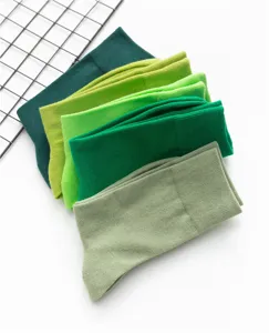 Nahaufnahme von gestapelten gruenen Baumwoll-Socken in verschiedenen Nuancen, weich.