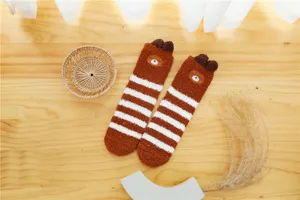 Detail shot of cozy brown and white striped plush winter socks with cute bear ears and embroidery.