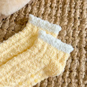 Gros plan détaillé de chaussettes duveteuses jaunes douillettes avec poignets blancs.