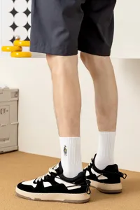 Vue détaillée de chaussettes mi-hautes blanches pour hommes avec jolie broderie et baskets.