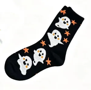 Detail view of black fuzzy plush Halloween socks featuring cute white ghost and orange star.