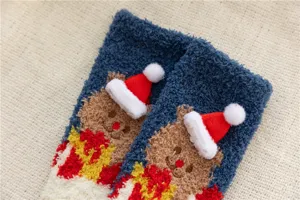 Gros plan de chaussettes de Noël duveteuses en polaire corail avec ours en peluche 3D et bonnet.