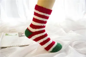 Red white striped fuzzy Christmas socks detail shot, cozy plush floor socks for winter home.