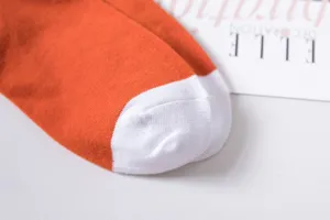 Close-up detail of women's orange and white cotton mid-calf socks toe seam texture.