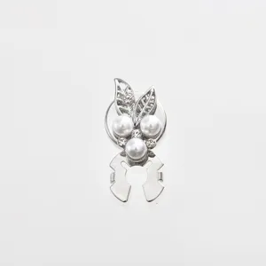 Closeup detail of silver alloy scarf clip decorated with sparkling rhinestones and white pearls.