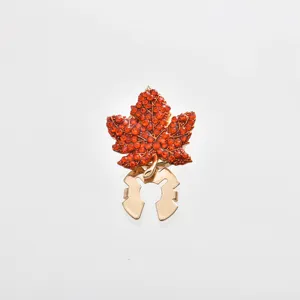 Close-up of the exquisite orange rhinestone maple leaf scarf buckle detail, glossy metal.