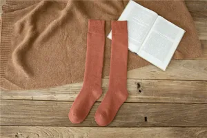 Detail shot of winter thick fleece-lined warm long socks on rustic wooden table background.
