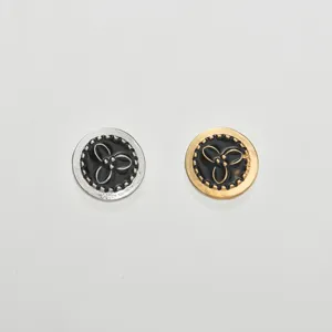 Detalle de gemelos de metal para camisa con esmalte negro y un delicado motivo floral.