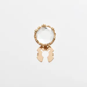 Close-up detail of golden crystal rhinestone shirt cufflink and decorative button accessory.