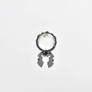 Detailed close-up of a sparkling clear gem cufflink with an ornate black metal claw setting.