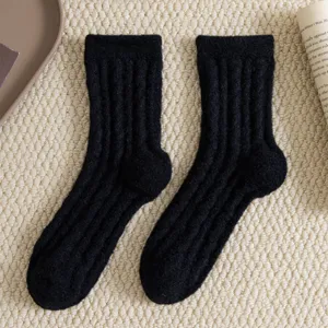 Nahaufnahme von schwarzen gerippten dicken warmen Wintersocken auf strukturierter Teppichfläche.